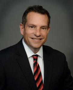 A man in suit and tie smiling for the camera.