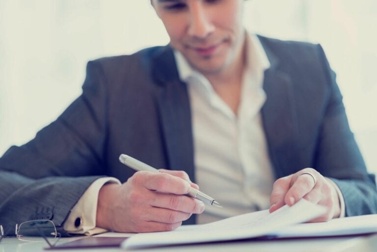 A man holding a pen for signing on a document